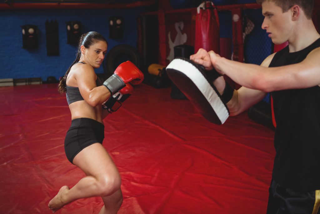 Female boxer practicing with trainer at fitness studio